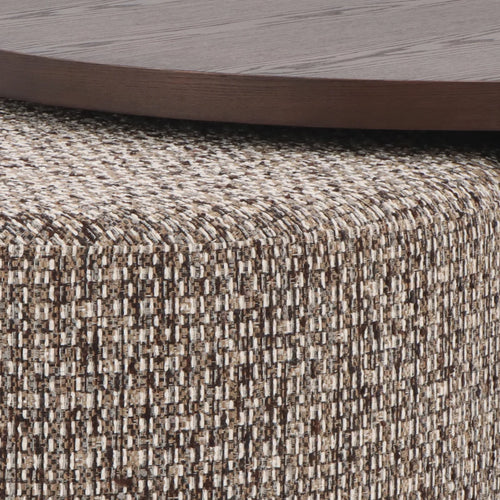 Close-up of a woven upholstered furniture surface in a heathered beige, brown, and off-white texture, with part of a dark wood tabletop visible at the top.