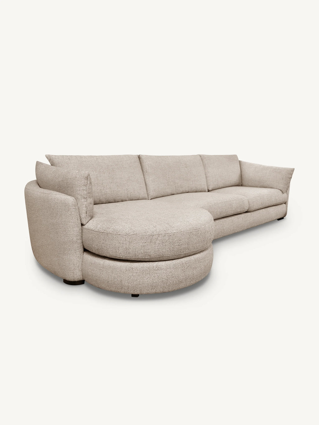A modern curved upholstered sofa in a light beige textured fabric, featuring a chaise lounge on the left side, photographed against a solid off-white background.