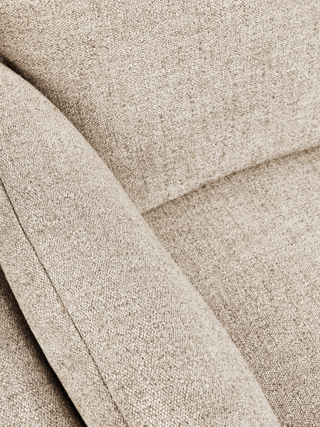 Close-up of a textured woven fabric in a warm light beige or taupe color, showing the material detail and stitched panel seams.