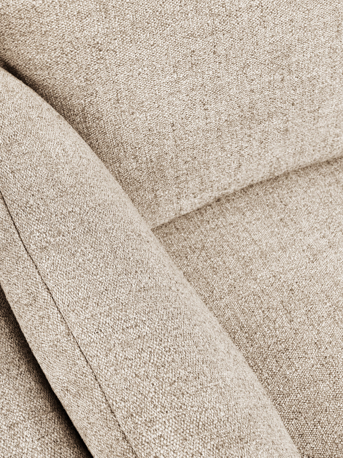 Close-up of a textured woven fabric in a warm light beige or taupe color, showing the material detail and stitched panel seams.