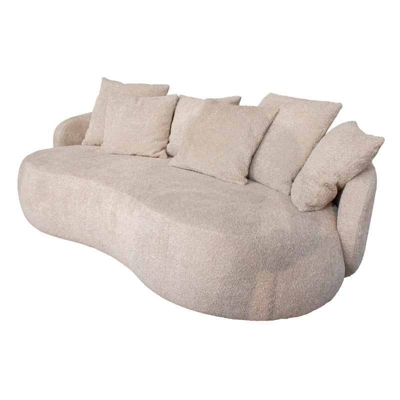 A curved, low-profile upholstered sofa with a textured bouclé fabric in a light beige color, featuring multiple matching throw pillows, shown against a plain white background.