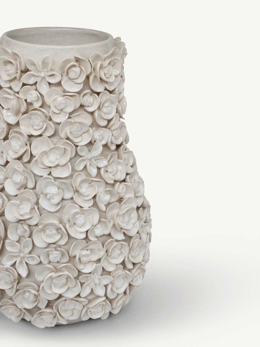 A textured ceramic vase covered in sculpted 3D flowers, shown on a clean off-white background.