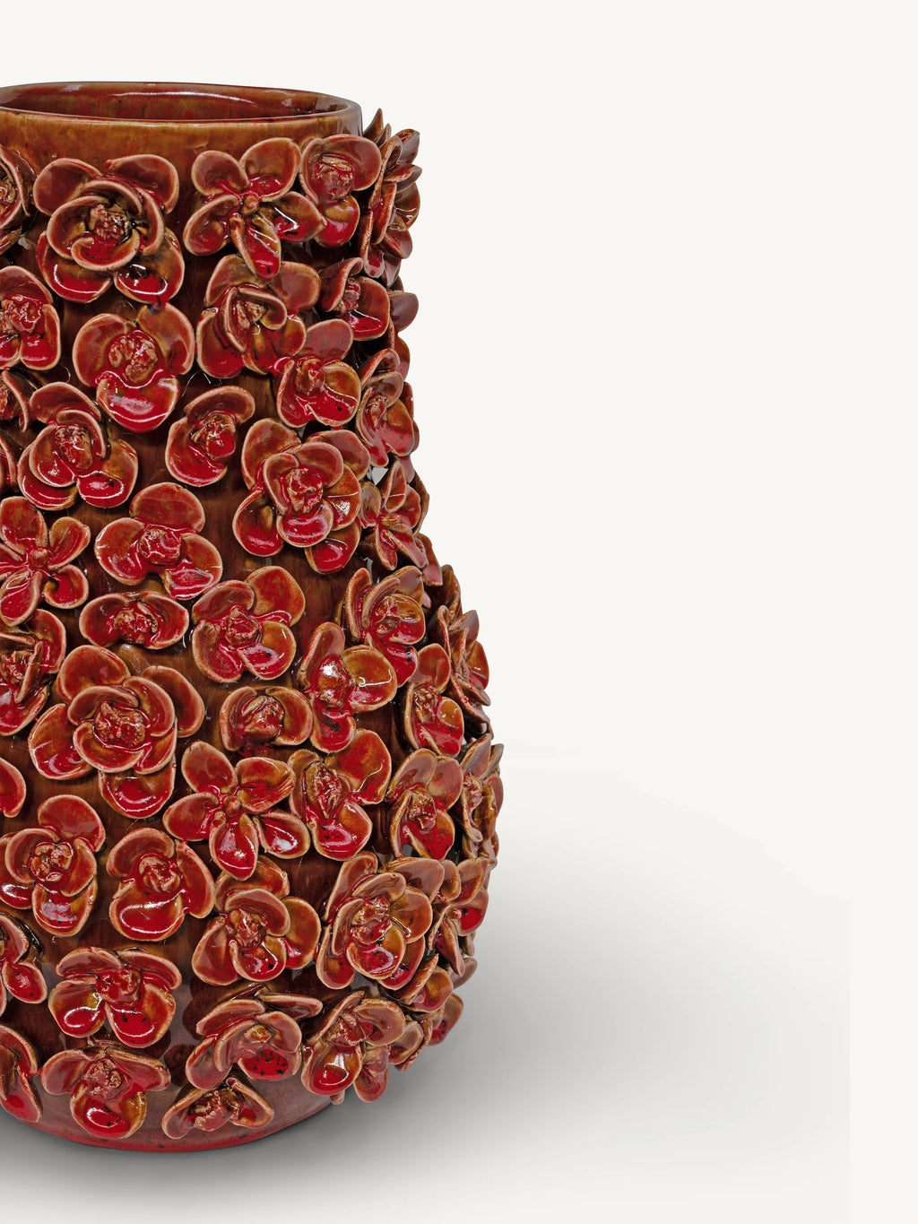 A close-up of a glossy brown ceramic vase covered in raised red floral relief patterns, shown against a plain light gray background.