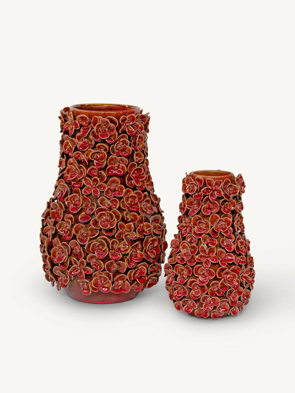 Two decorative ceramic vases covered in raised red and pink floral relief patterns, shown on a clean off-white background.