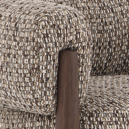 Close-up of a textured woven upholstery fabric in beige, brown, and cream tones, with a dark brown wooden armrest visible.